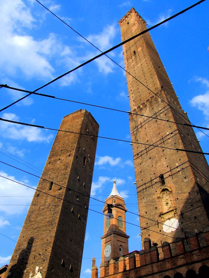 Piazza di Porta Ravegnana, Bologna. A triangle of wires formed by cables suspended before the two towers of the Piazza di Porta Ravegnana, 40126 Bologna, Italy. The 48m high Garisenda Tower was built around the same time as the Asinelli tower standing next to it. There is no public access. The 97.2m high Asinelli Tower was built between 1109 and 1119 by the Asinelli family and public access is allowed. The inner staircase of 498 steps was completed in 1684. https://witness.theguardian.com/assignment/55718213e4b019d982cba15c/1560801
