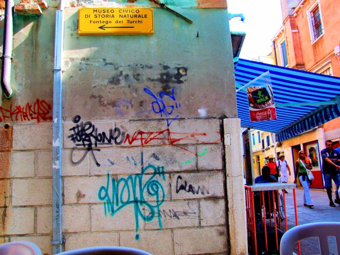 An Arrow Is An Arrow In Any Language. An arrow pointing the way to the Museo Civico Di Storia Naturale, Fontego dei Turchi, Venezia or should I say the Natural History Museum in the Turkish Foundation Building in Venice – with some street art thrown in for free. https://witness.theguardian.com/assignment/558c23e6e4b003b03c641510/1595487